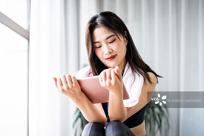 年轻亚裔女性在健身房看她的iPad图片素材