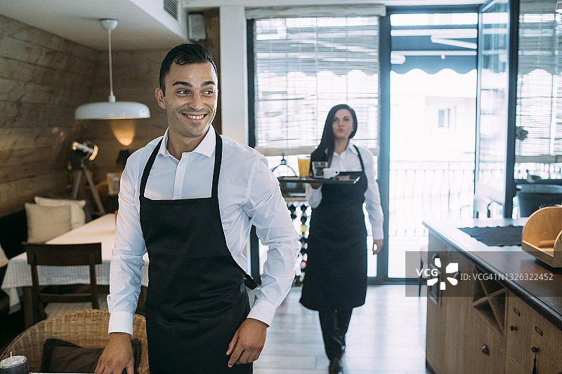 餐厅里工作的年轻男服务员和他的同事图片素材