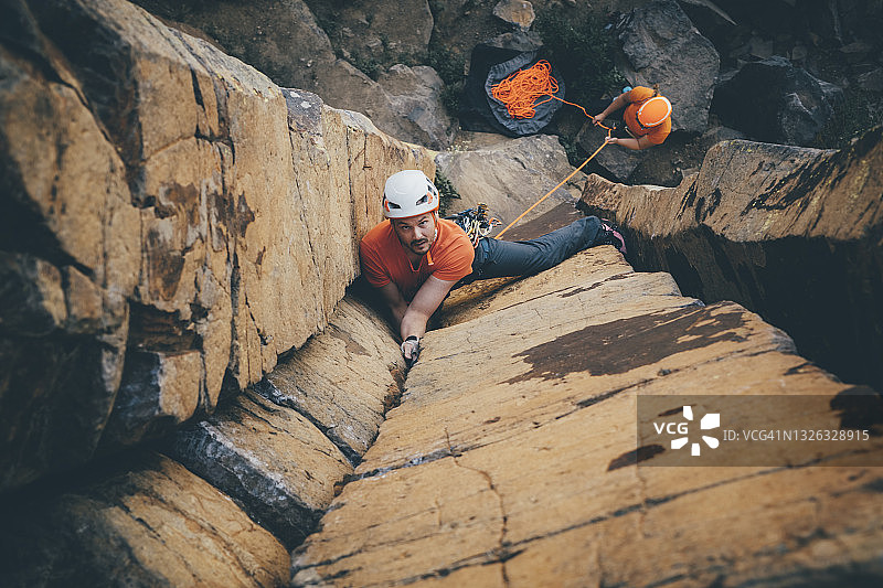 俯视拍摄：一位男性攀岩者在弗农附近攀登玄武岩柱时抬头看着相机图片素材