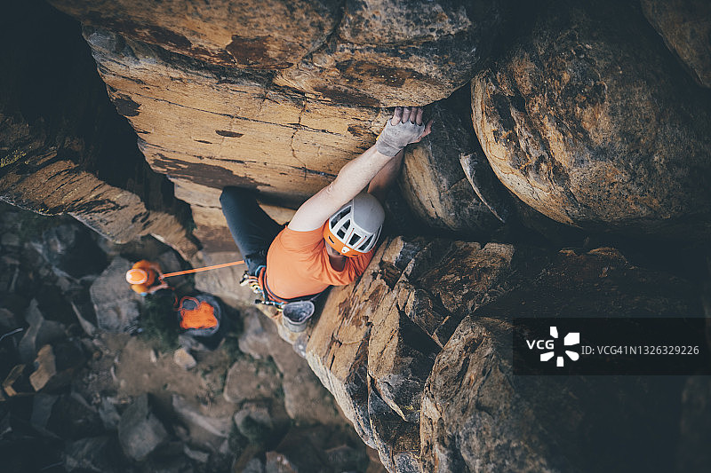 一名男性攀岩者抓住沙漠悬崖上的把手的顶视图图片素材