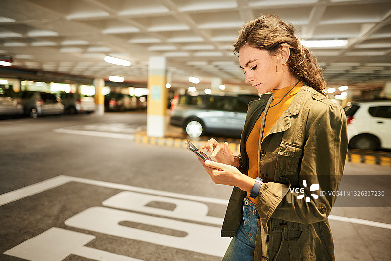 女人在停车场边走边查看手机应用图片素材