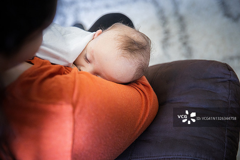 母乳喂养时，母亲摇晃着哄新生儿入睡图片素材
