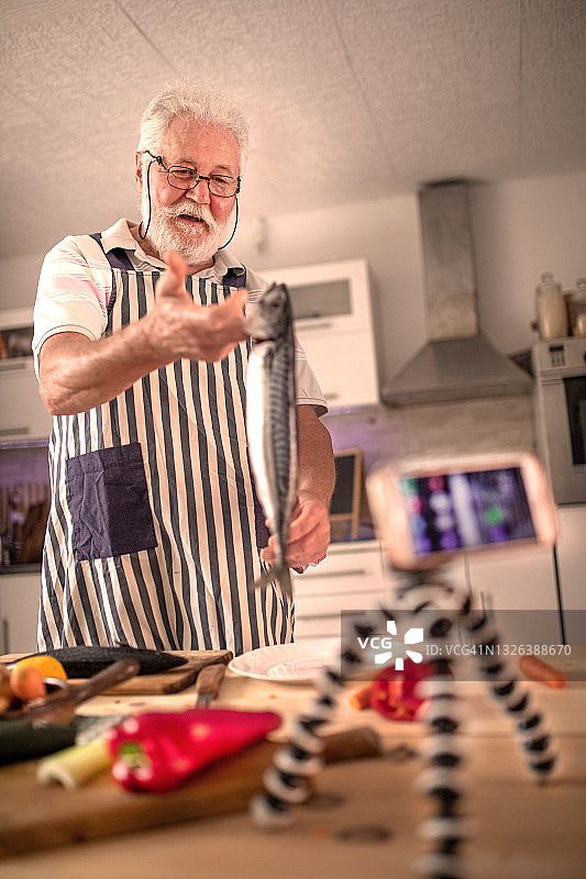 老年男人在厨房准备鱼图片素材