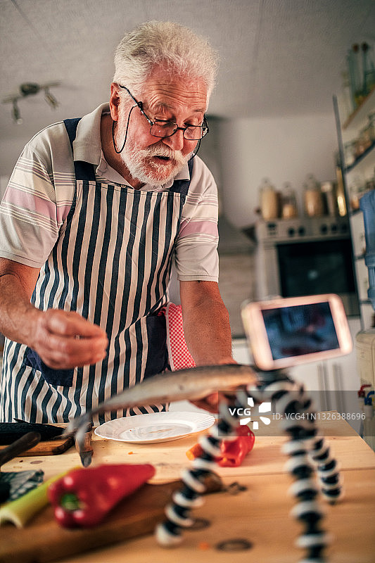 老年男人在厨房准备鱼图片素材