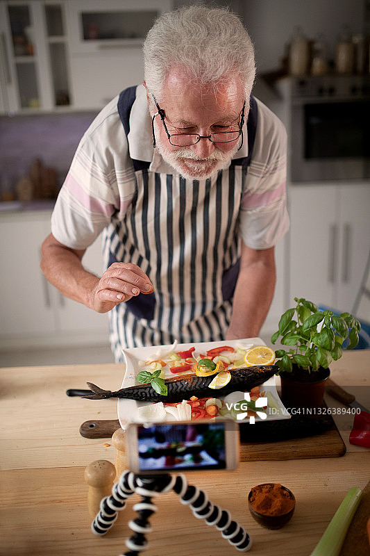 老年男人在厨房准备鱼图片素材