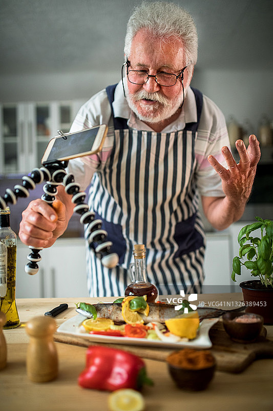 老年男人在厨房准备鱼图片素材