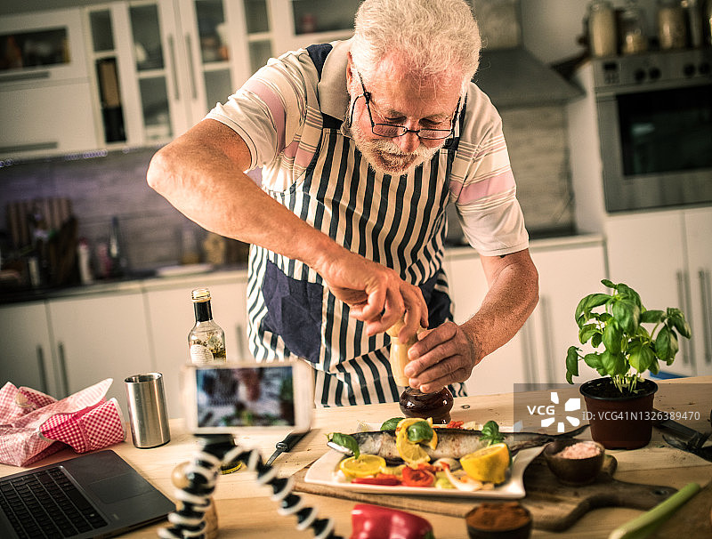 老年男人在厨房准备鱼图片素材