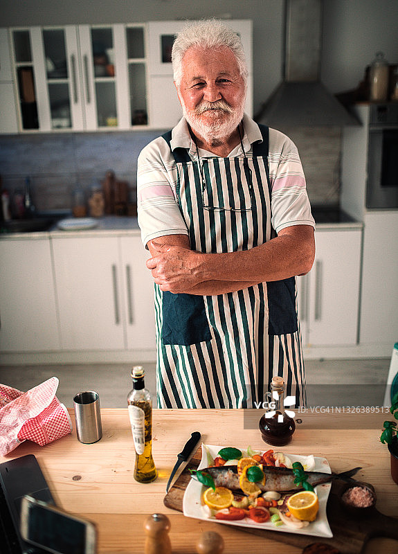 老年男人在厨房准备鱼图片素材