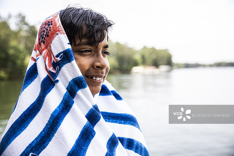 在湖边，男孩头上搭着毛巾微笑图片素材