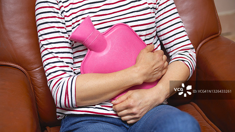 坐在椅子上抱着热水袋的女人图片素材