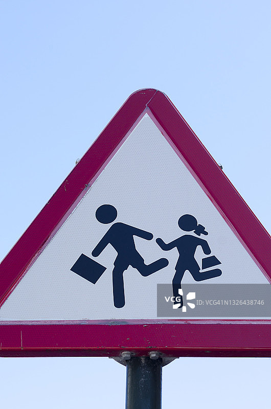 小学生在交通警告标志前过马路图片素材