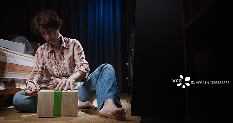 女人坐在地板上打开一个盒子图片素材