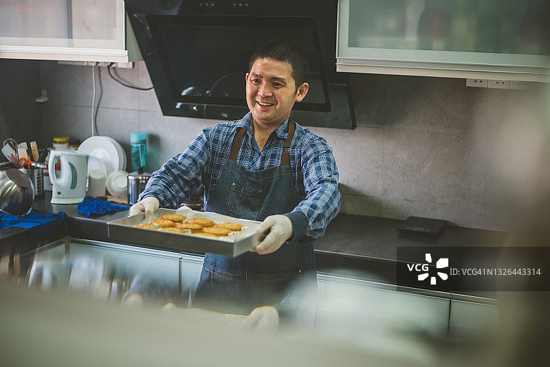 亚洲男人手捧自制中国月饼，准备放入烤箱烘烤，支持本地小企业图片素材