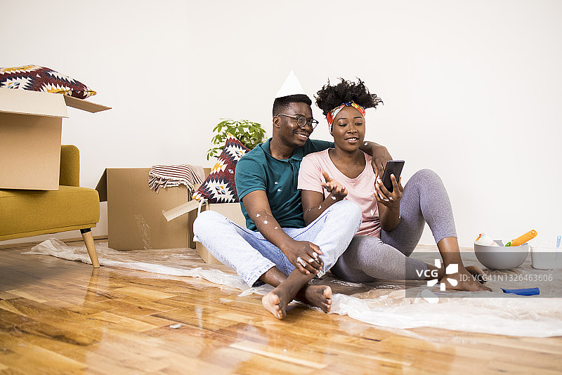 快乐的非裔美国人夫妇在粉刷房子时停下来上网图片素材