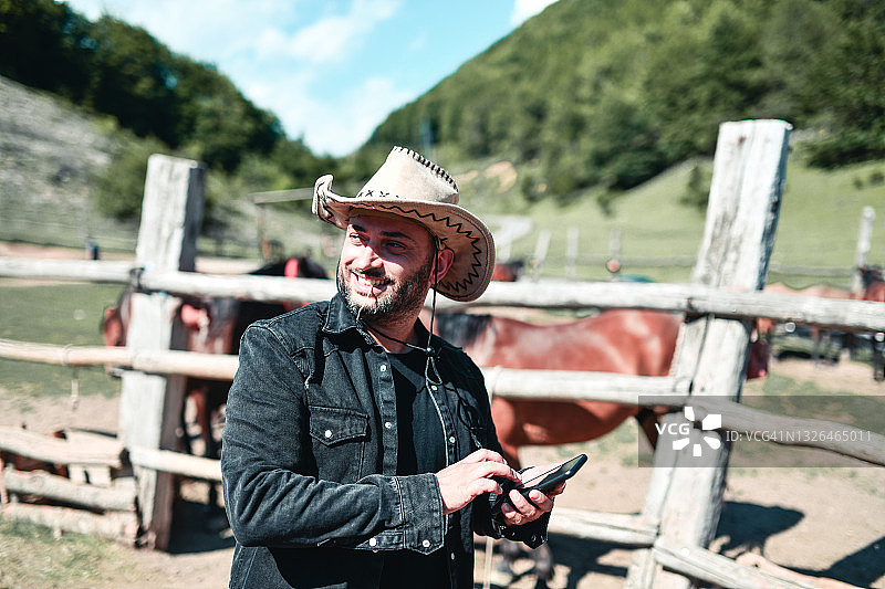 牧场主在山地牧场通过智能手机推广骑马旅游项目图片素材