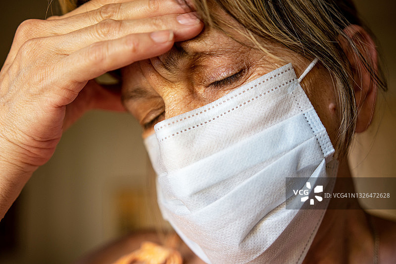 戴医用口罩中年妇女头痛，疾病疫情概念图片素材