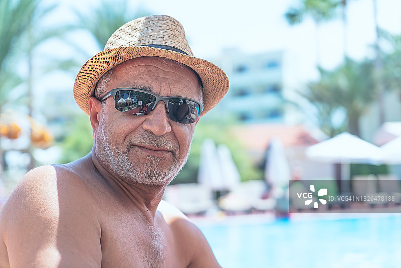 退休老人在豪华酒店泳池边晒日光浴图片素材