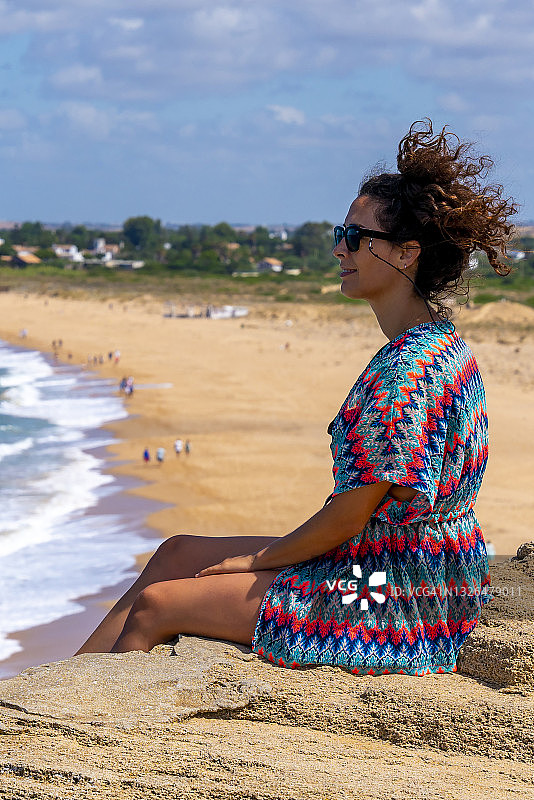 女人坐在海滩的岩石上图片素材
