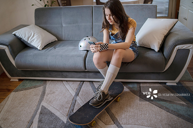 青少年准备去玩滑板，正在查看手机图片素材