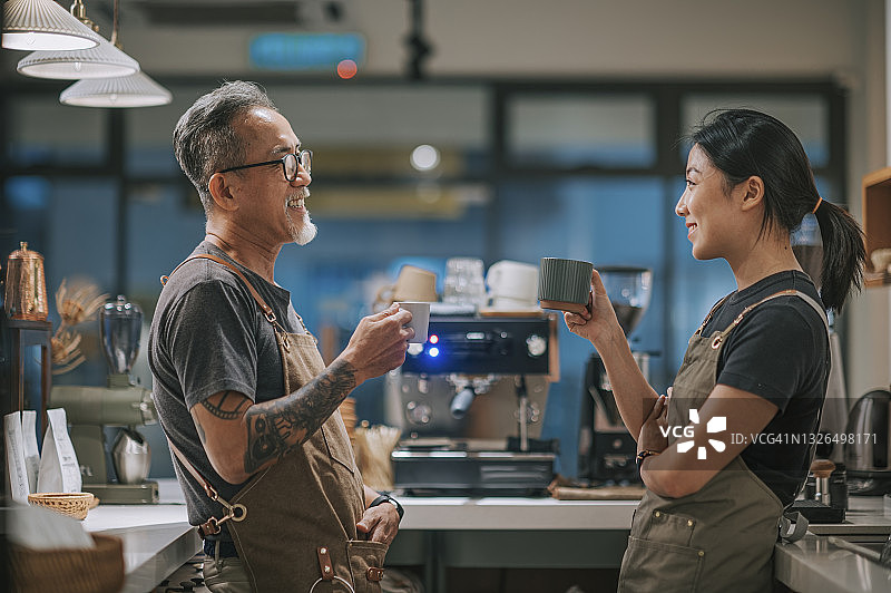 中国年长的咖啡店男老板和女儿们在吧台旁喝咖啡聊天图片素材