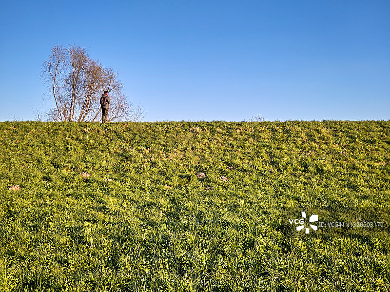 孤独的男人在春天的堤坝上图片素材