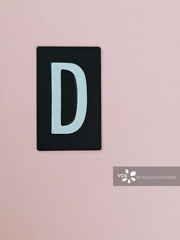 粉色背景上的黑色盘子里的白色字母D图片素材