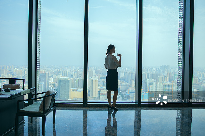 女商人喝咖啡，望着办公室窗外图片素材