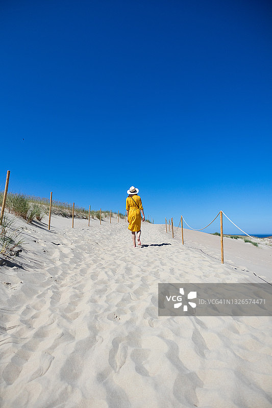 在海滩上穿黄色连衣裙的女人图片素材