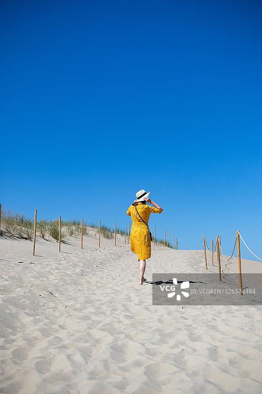 在海滩上穿黄色连衣裙的女人图片素材