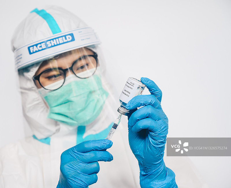 医护人员拿着新冠疫苗瓶，同时用注射器抽取药物图片素材