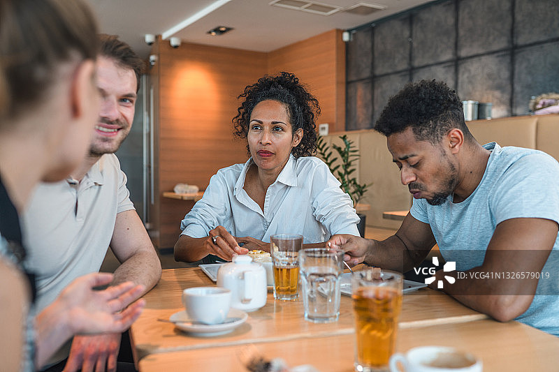在咖啡馆里一起享受时光的多元种族朋友图片素材