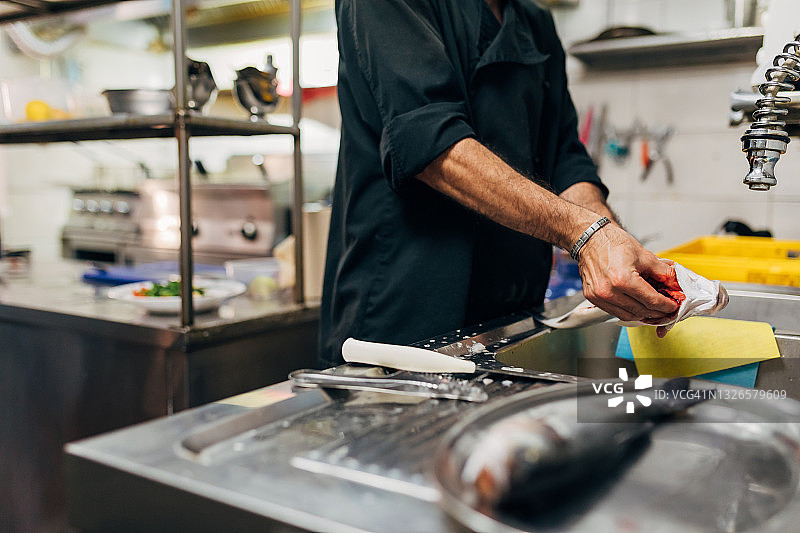 厨房水槽上方：男厨师正在清洗鲈鱼内脏图片素材