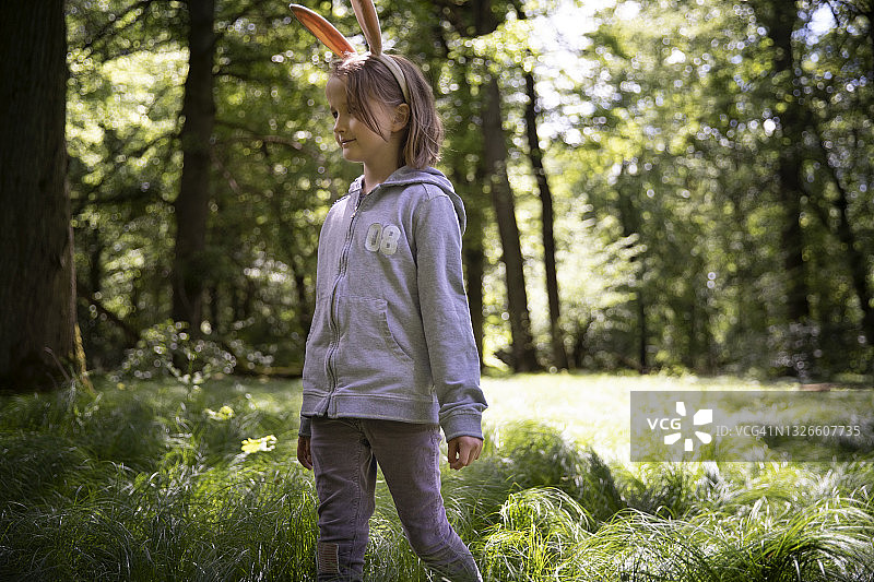 戴兔子耳朵的微笑儿童在春日草地图片素材