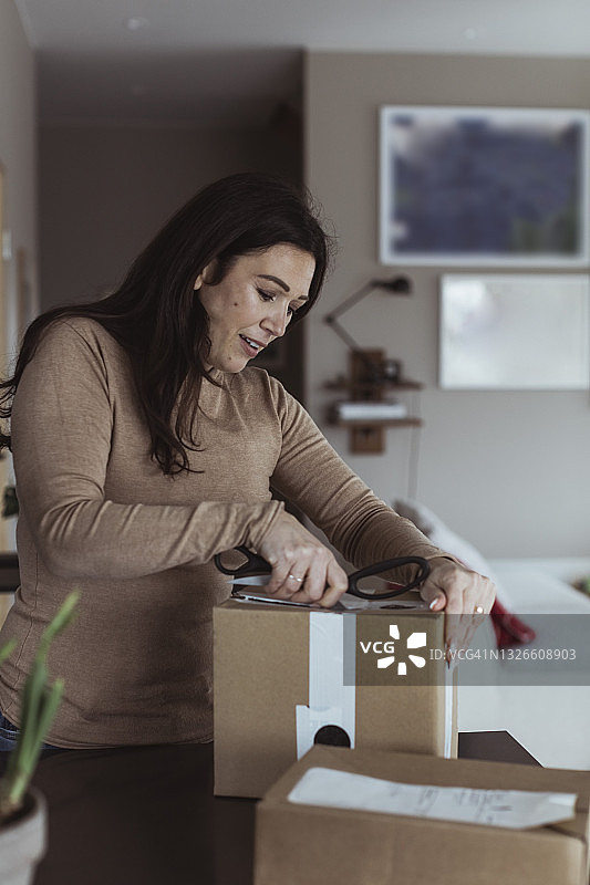 中年妇女在家用剪刀打开箱子图片素材