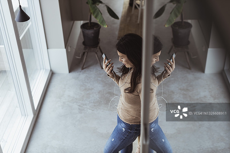 在家里戴着入耳式耳机听音乐的女人图片素材