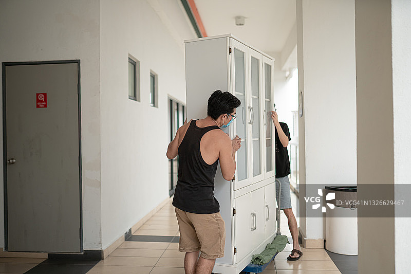 两名中国男子在办公室走廊搬运文件柜图片素材