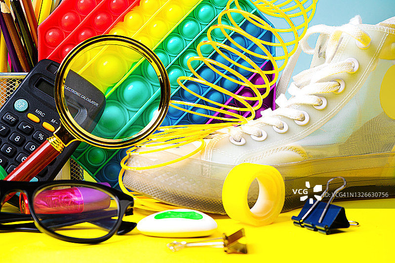 色彩缤纷的返校背景，带有儿童抗压百变玩具、白色运动鞋和学校用品图片素材