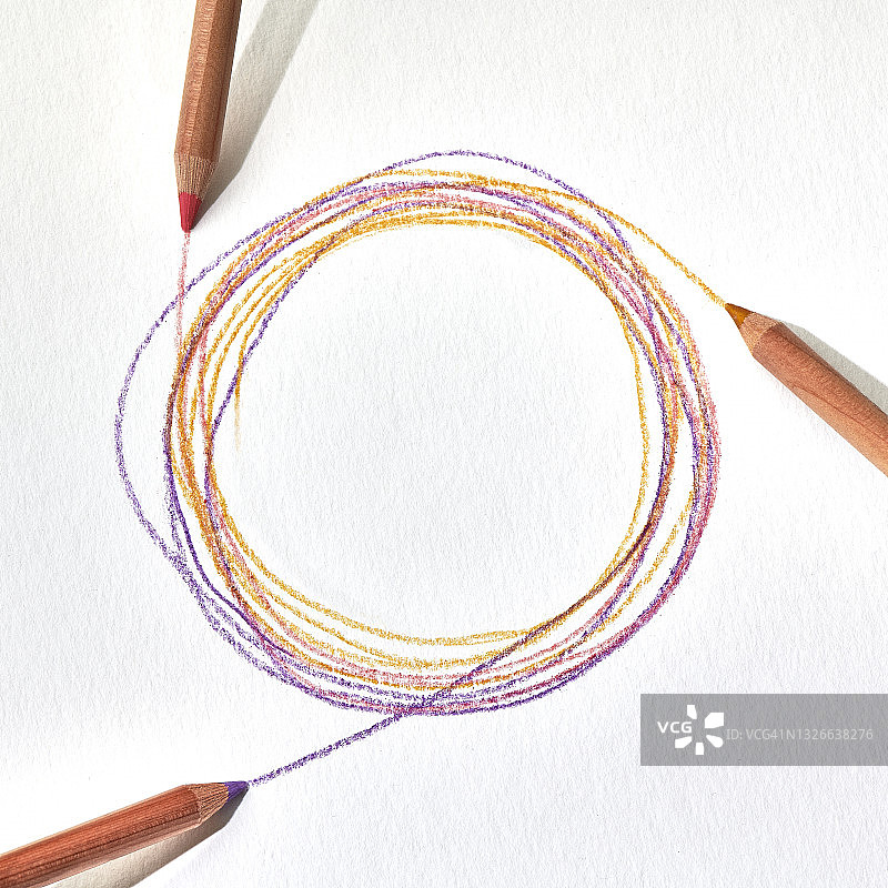 三支彩色铅笔在白色纸上绘制重叠的圆圈图片素材