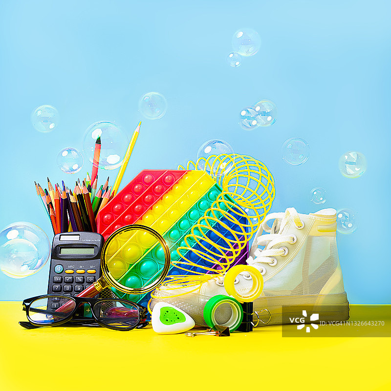 色彩缤纷的返校背景与儿童抗压玩具、白色运动鞋、肥皂泡和学习用品图片素材