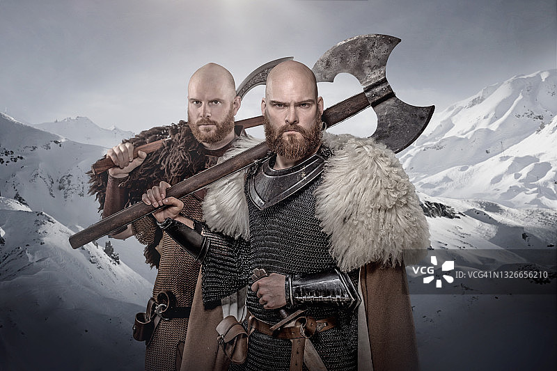 两名手持武器、浴血奋战的维京战士，背景是山脉图片素材