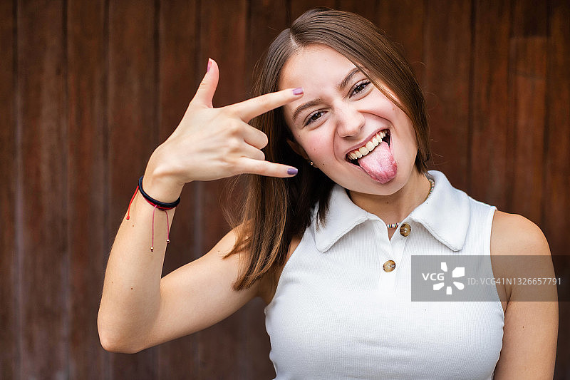 看着镜头并做重金属手势的年轻墨西哥女性图片素材