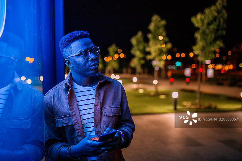 在霓虹灯闪烁的街道上使用手机图片素材