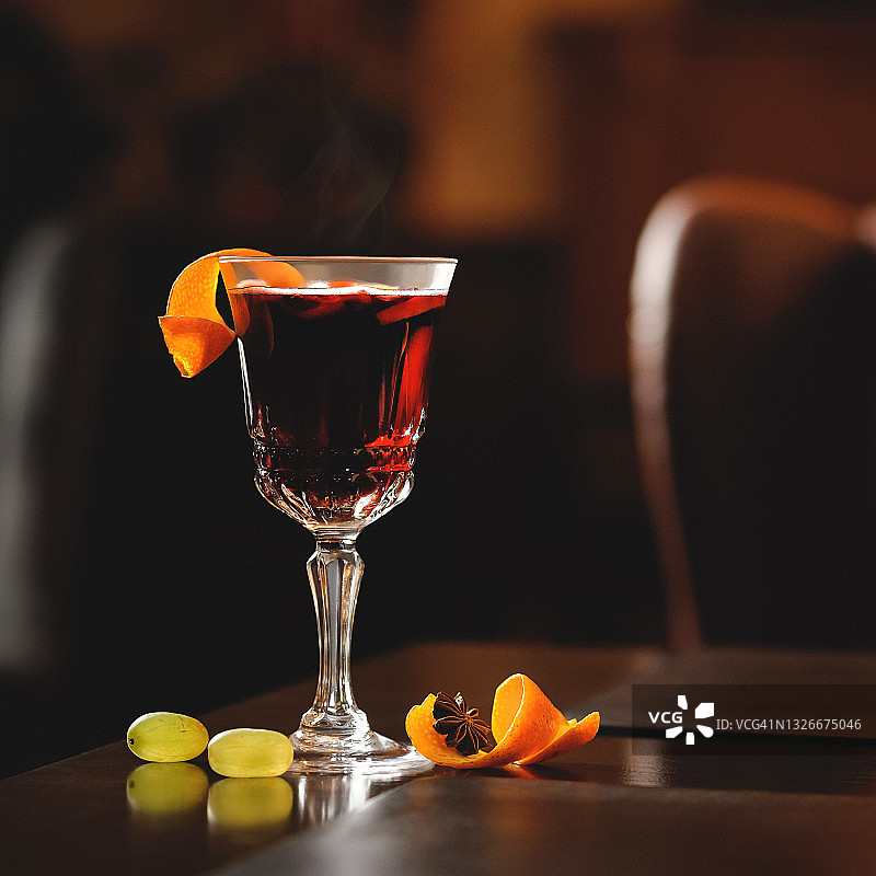 桌上的桑格利亚浆果酒，配有葡萄和橙皮。红色酒精饮料的背光水晶玻璃。右侧的复制空间图片素材