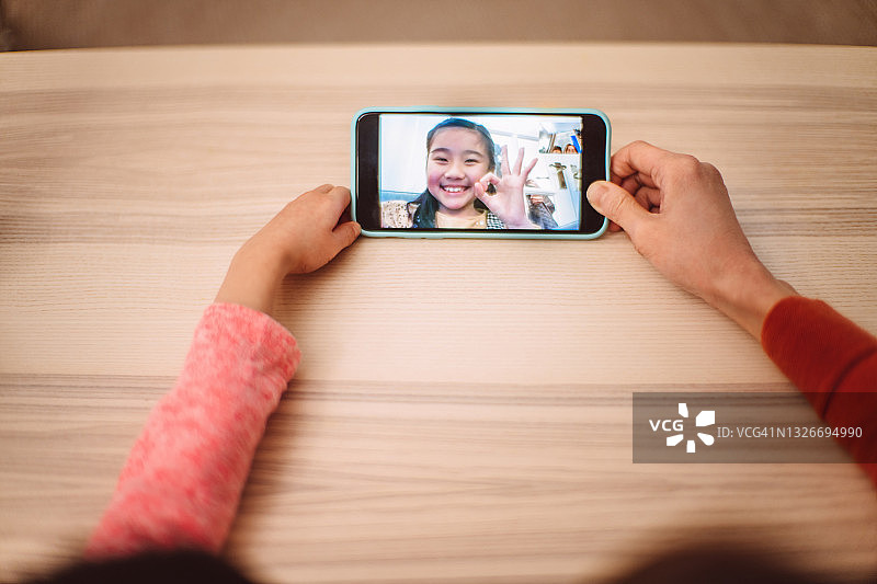 俯视：妈妈和女儿在家中与家人进行视频通话图片素材