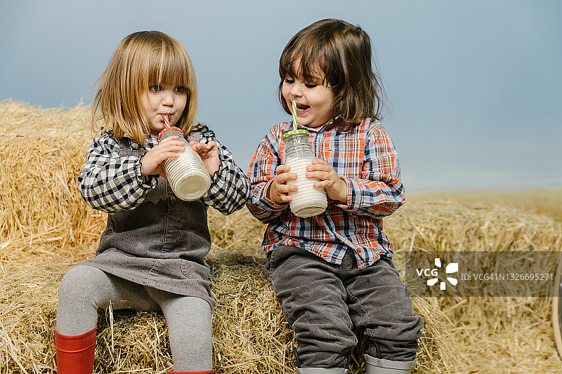 坐在草垛上喝牛奶的孩子图片素材