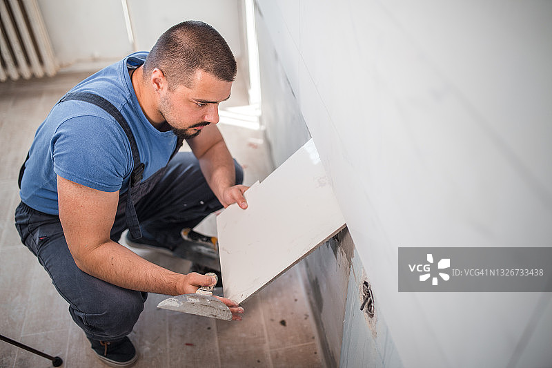 穿着工作服的工人在专注地粘贴厨房瓷砖图片素材