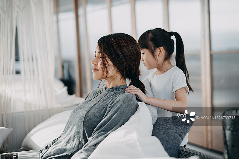 亚裔女孩在家为母亲按摩肩膀图片素材