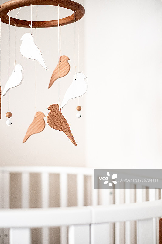 婴儿房特写：白色婴儿床和悬挂的摇铃图片素材