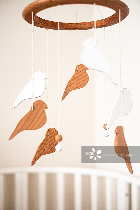 婴儿房特写：白色婴儿床和悬挂的摇铃图片素材