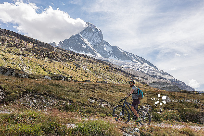 男人在马特洪峰下的山路上骑山地自行车图片素材